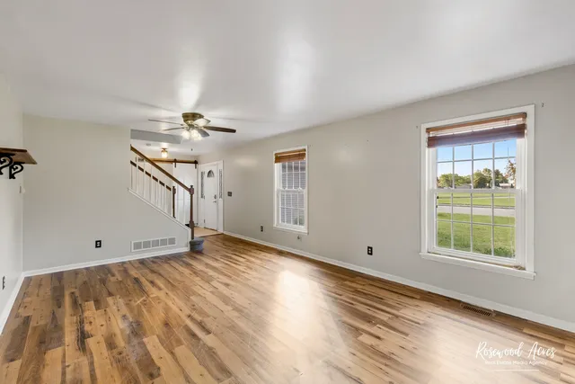 a view of empty room with wooden floor and fan