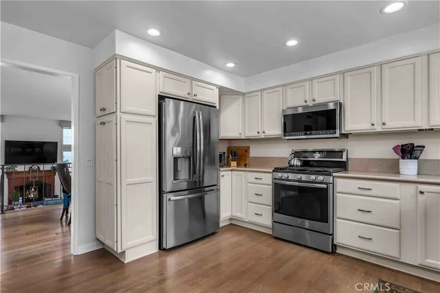 a kitchen with stainless steel appliances a refrigerator stove and white cabinets