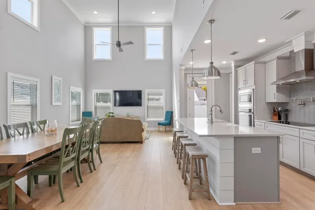 a kitchen with stainless steel appliances kitchen island granite countertop a refrigerator a sink dishwasher a dining table and chairs with wooden floor