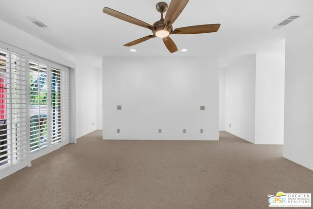 an empty room with windows and fan