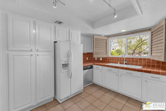 a large white kitchen with a sink and refrigerator