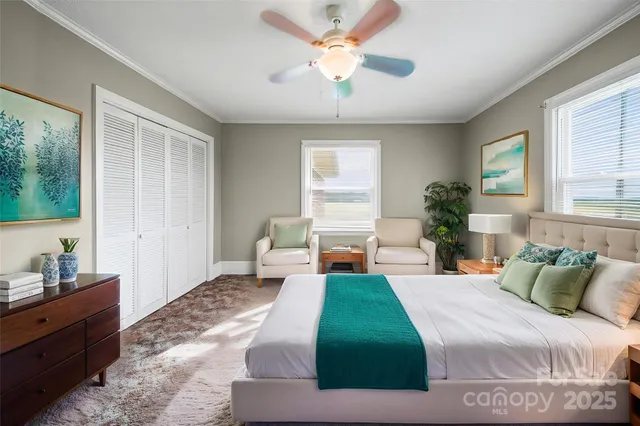 a bedroom with a large bed and a chandelier fan