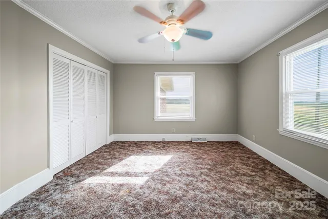 a view of an empty room and window and chandelier fan