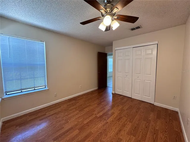 a view of an empty room with a window and wooden floor