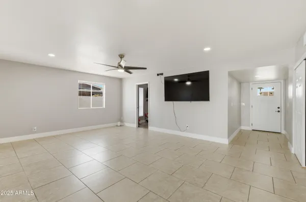 a view of an empty room with a window and a kitchen