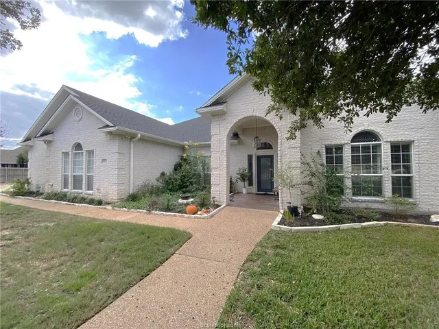 a front view of a house with a yard and potted plants