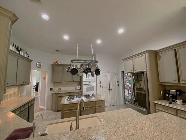 a kitchen with stainless steel appliances kitchen island granite countertop a refrigerator and a stove top oven