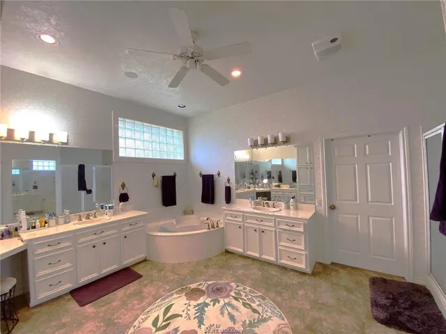 a large white bathroom with a double vanity sink a mirror and a bathtub