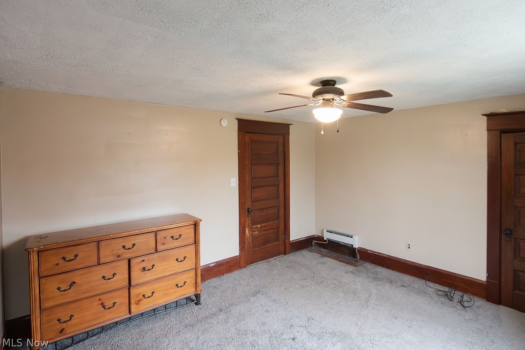 1195 South Johnson Road Sebring, OH 44672 - Photo 17 of 34 Unfurnished bedroom with carpet floors, a ceiling fan, a textured ceiling, and a baseboard radiator