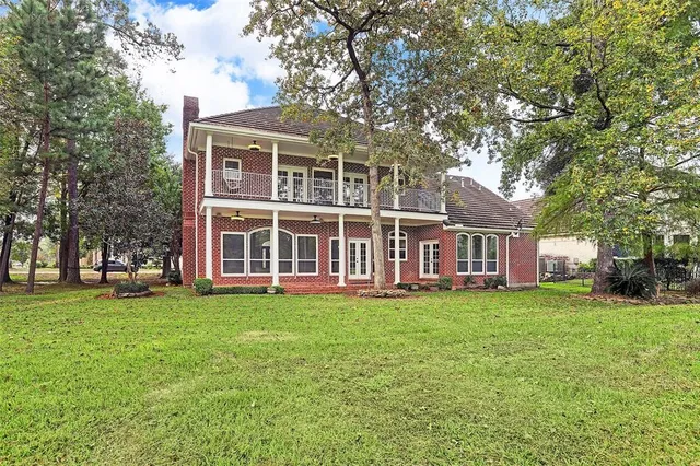 front view of a brick house with a big yard and large trees