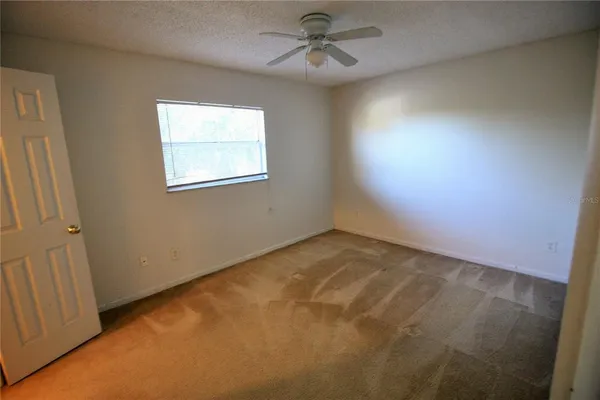 an empty room with windows and fan