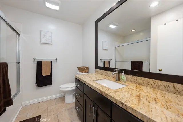 a bathroom with a granite countertop sink a large mirror and toilet