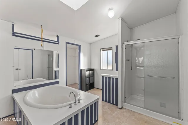a spacious bathroom with a tub double sink and mirror