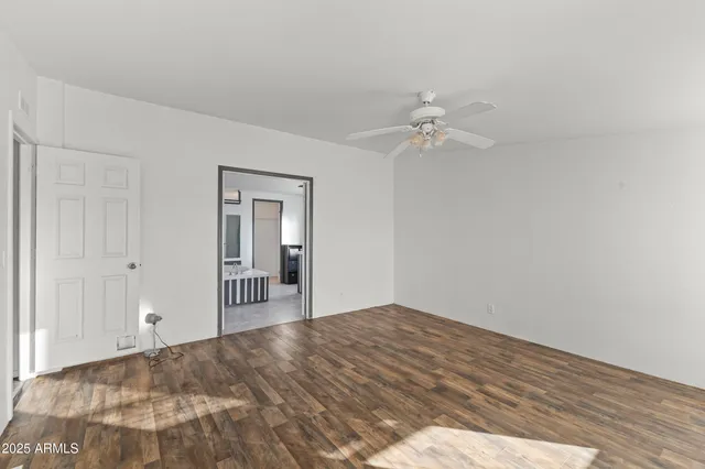an empty room with wooden floor chandelier fan and windows