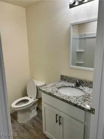 a bathroom with a granite countertop toilet and a sink