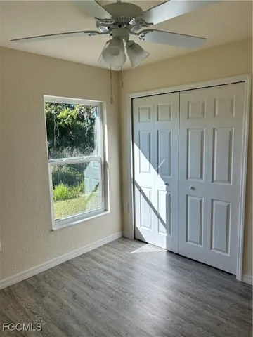 an empty room with wooden floor fan and windows