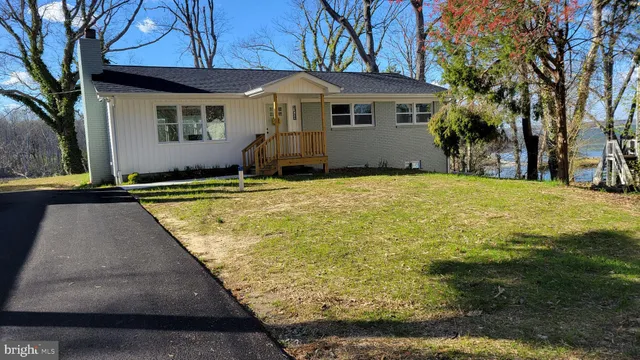 a backyard of a house with large trees and table and chairs under an umbrella
