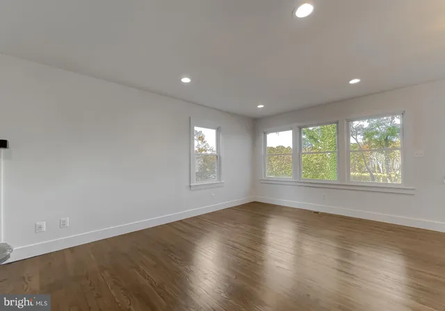 a view of a kitchen and an empty room with wooden floor and a kitchen