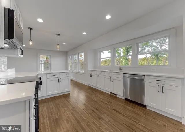 a view of an empty room with wooden floor and a ceiling fan