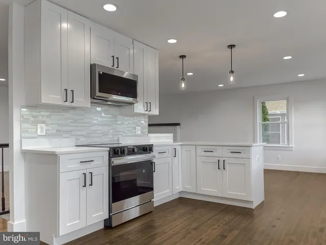 an empty room with wooden floor a ceiling fan and windows