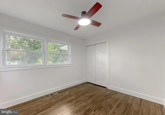 a view of empty room with wooden floor and fan