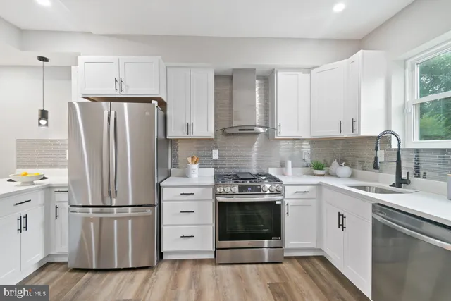 a kitchen with stainless steel appliances a stove a sink dishwasher a refrigerator and a stove with wooden floor