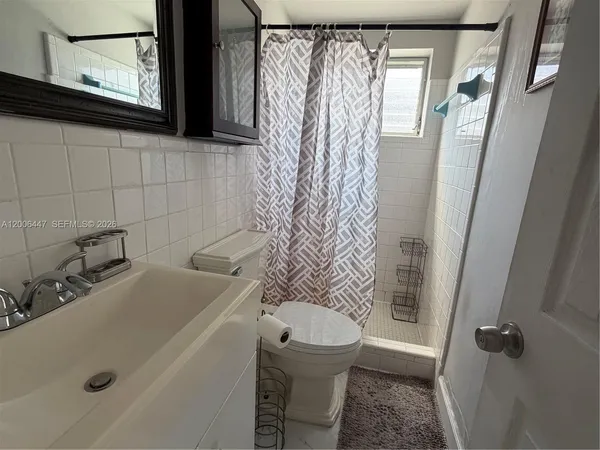a bathroom with a sink a toilet and shower curtain
