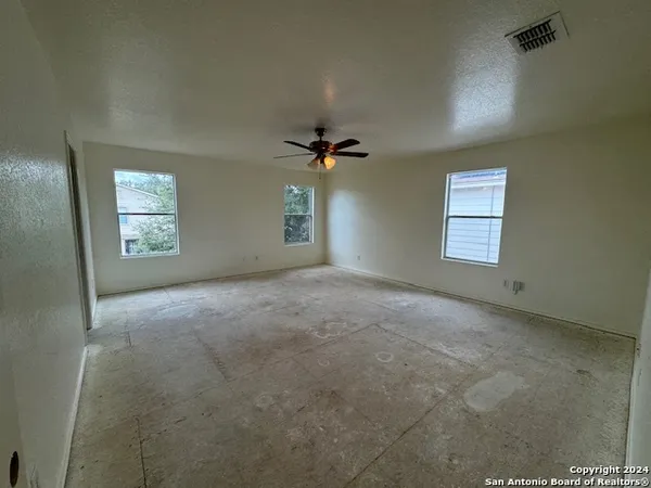 an empty room with windows and ceiling fan