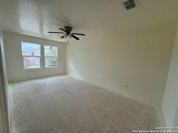 an empty room with windows and fan