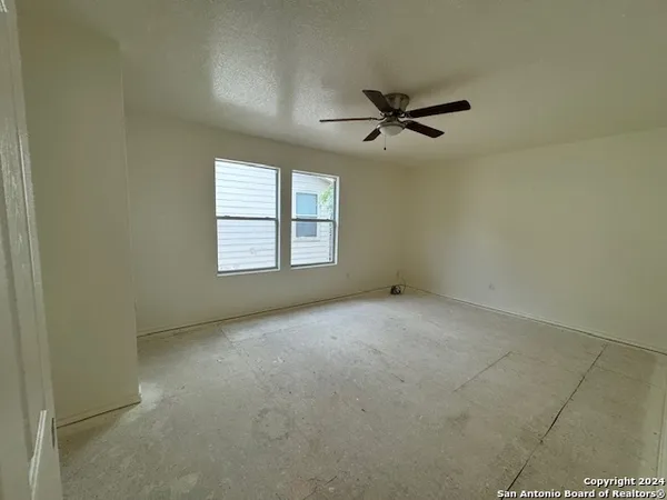 an empty room with windows and ceiling fan view