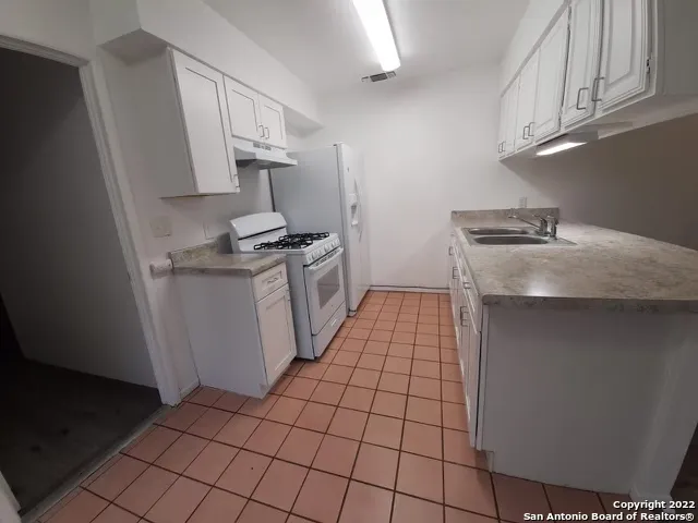 a kitchen with granite countertop a sink stove and cabinets