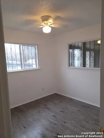 an empty room with wooden floor and windows