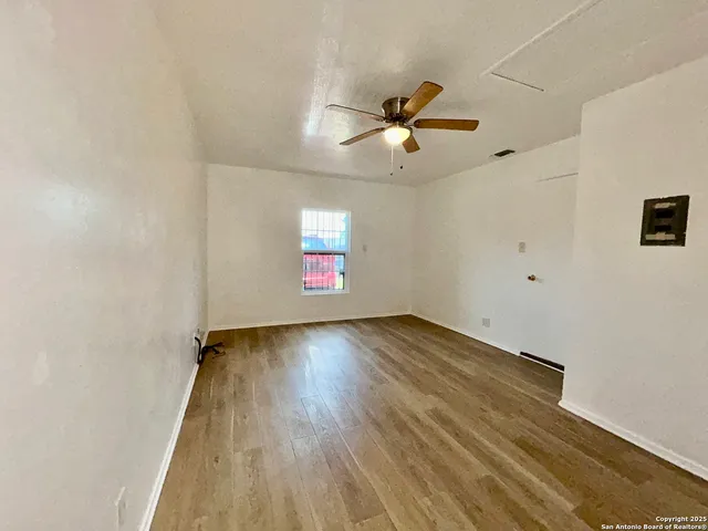 an empty room with wooden floor and windows