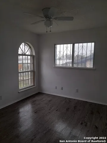 an empty room with wooden floor chandelier and windows
