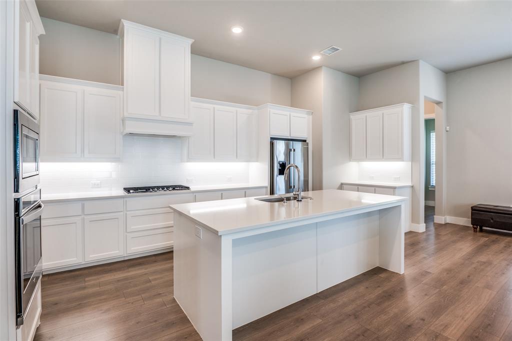2901 Quinton Street Prosper, TX 75078 - Photo 11 of 24 a kitchen with kitchen island granite countertop a sink stainless steel appliances and cabinets