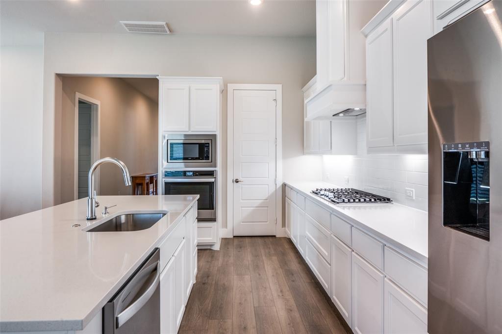 2901 Quinton Street Prosper, TX 75078 - Photo 12 of 24 a kitchen with kitchen island a counter top space a sink stainless steel appliances and cabinets