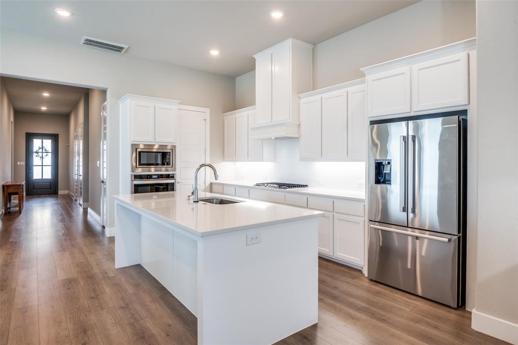 2901 Quinton Street Prosper, TX 75078 - Photo 10 of 24 a kitchen with kitchen island a sink appliances and cabinets