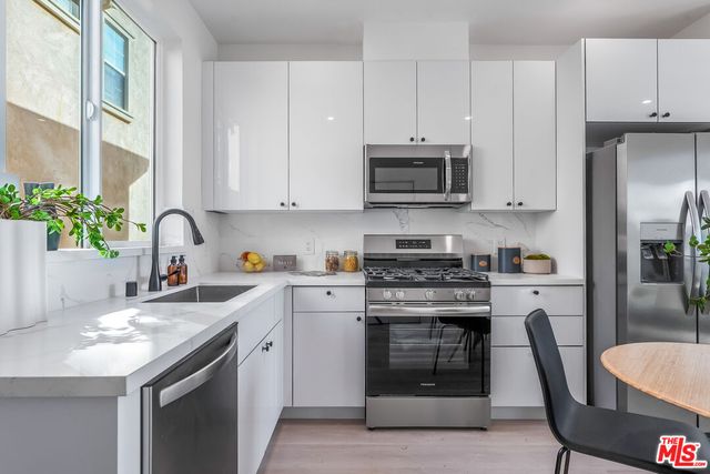 a kitchen with stainless steel appliances granite countertop a stove a sink dishwasher and a refrigerator