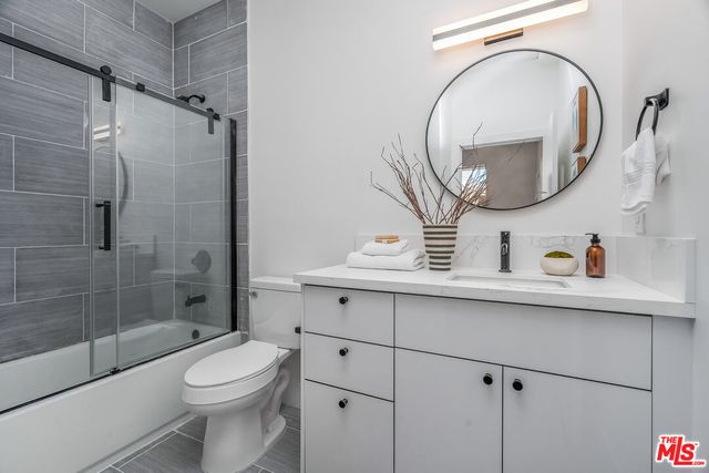 a bathroom with a sink a mirror a toilet and shower