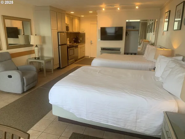 a large bedroom with a bed and a view of kitchen