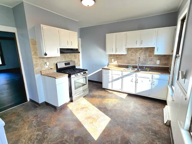 a kitchen with stainless steel appliances granite countertop a stove a sink and a microwave