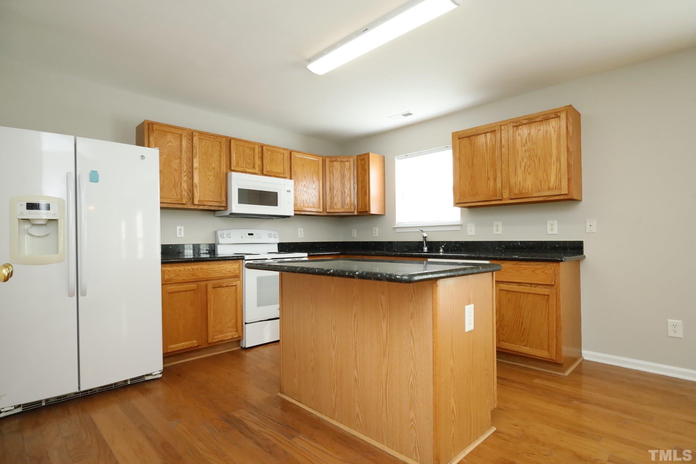 4014 Springfield Creek Drive Raleigh, NC 27616 - Photo 11 of 36 a kitchen with granite countertop wooden floors white cabinets and stainless steel appliances
