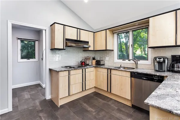 a kitchen with stainless steel appliances granite countertop a stove a sink and white cabinets