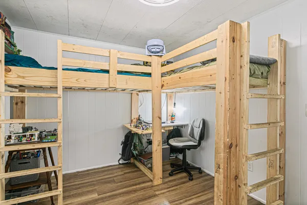 a view of a hallway to room with wooden floor and windows