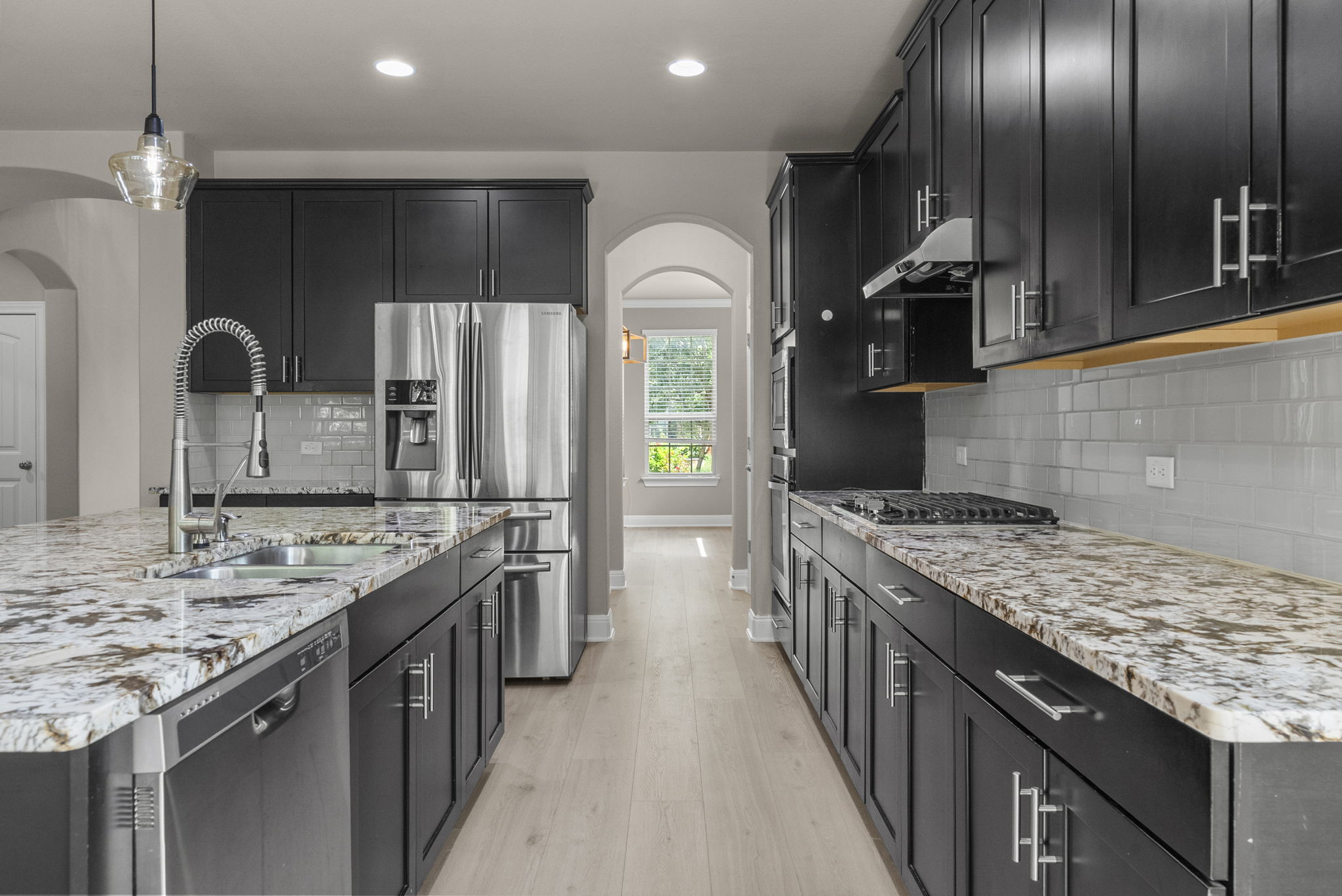 4401 Trinity Woods Street Leander, TX 78641 - Photo 11 of 37 Culinary aspirations come alive in this kitchen, featuring sleek dark cabinetry and elegant granite counters.