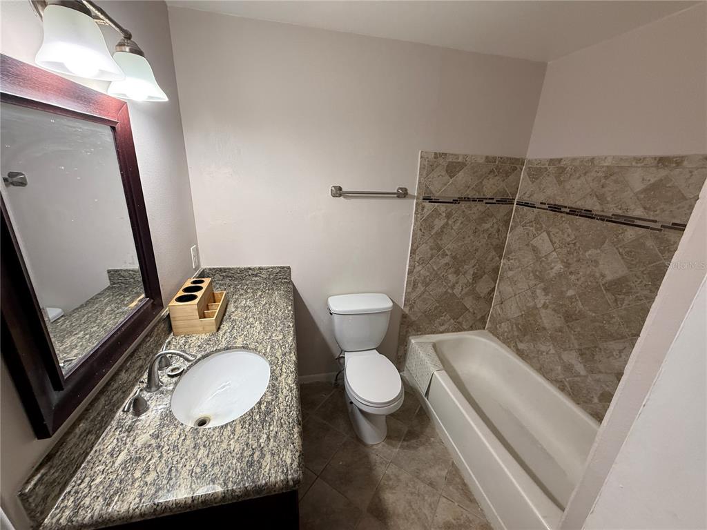 5120 East Temple Heights Road, Unit D Tampa, FL 33617 - Photo 12 of 14 a bathroom with a granite countertop sink mirror vanity and toilet