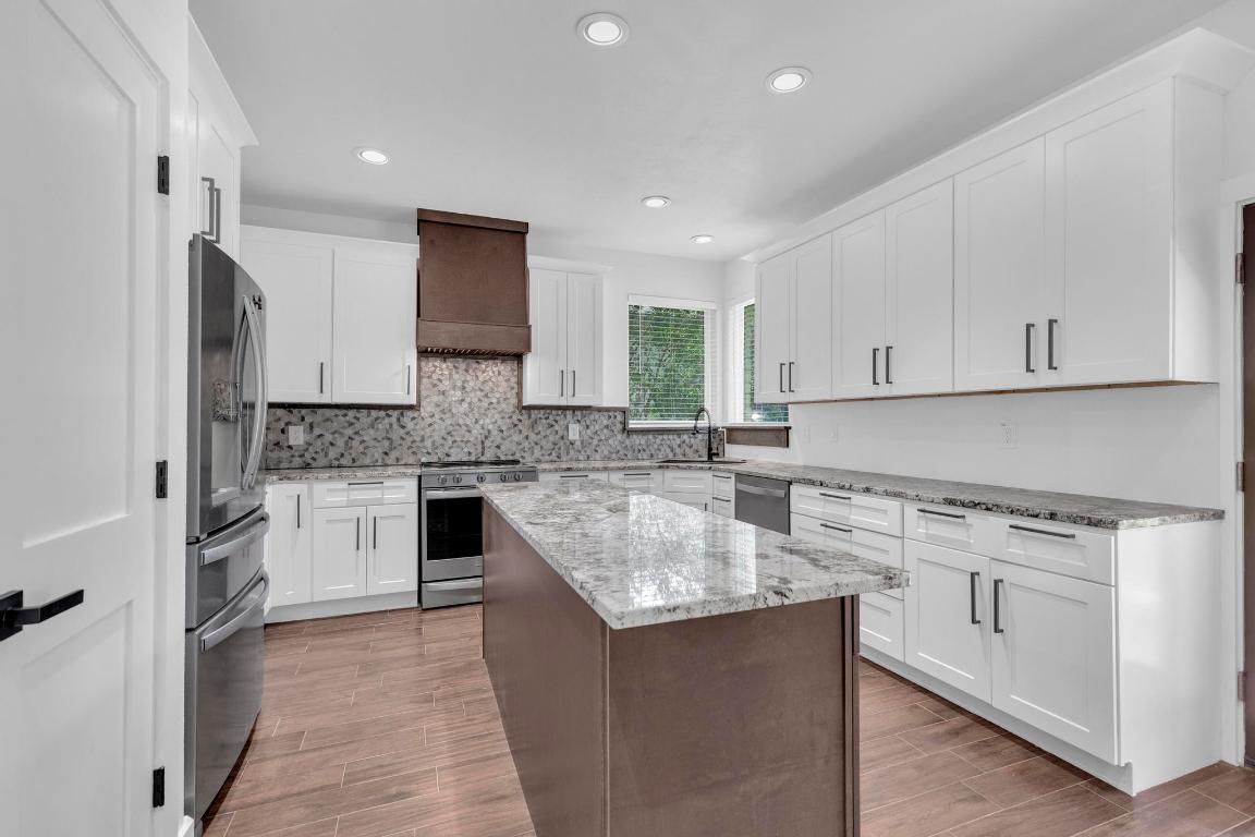 326 Coventry Road Spicewood, TX 78669 - Photo 14 of 30 a kitchen with stainless steel appliances granite countertop a stove a sink and a refrigerator