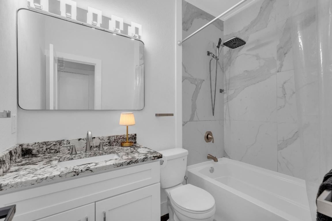 326 Coventry Road Spicewood, TX 78669 - Photo 21 of 30 a bathroom with a granite countertop sink a toilet and bathtub