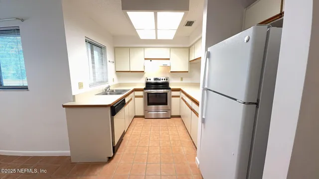 a kitchen with a refrigerator a sink and wooden floor