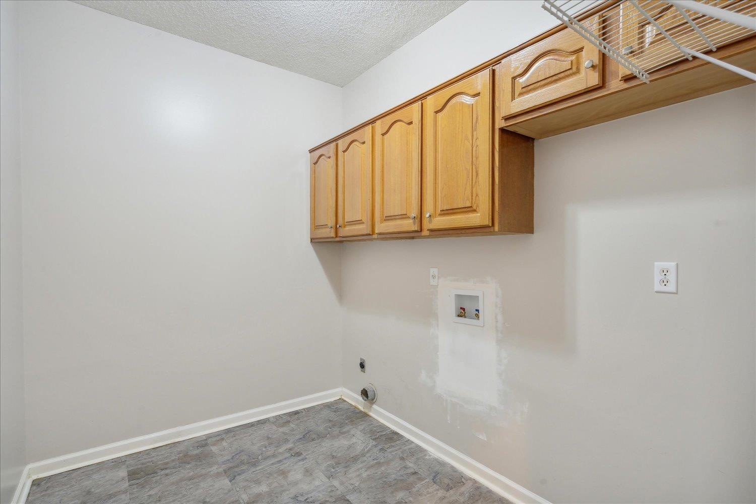 8817 Dexter Road Memphis, TN 38016 - Photo 19 of 34 Washroom featuring hookup for a washing machine, dark tile floors, a textured ceiling, hookup for an electric dryer, and cabinets